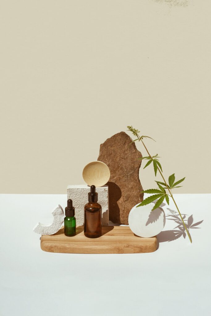 Various glass bottles with CBD oil, THC tincture and hemp leaves on beige background. minimalism